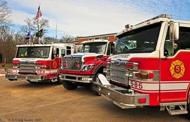 Three-apparatus lineup front-quarter view showing bumpers and cabs