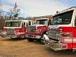Three-apparatus lineup front-quarter view showing bumpers and cabs