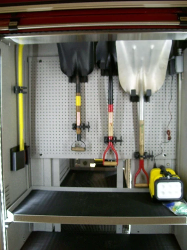 Open compartment showing hand tools, lighting equipment, and storage bins