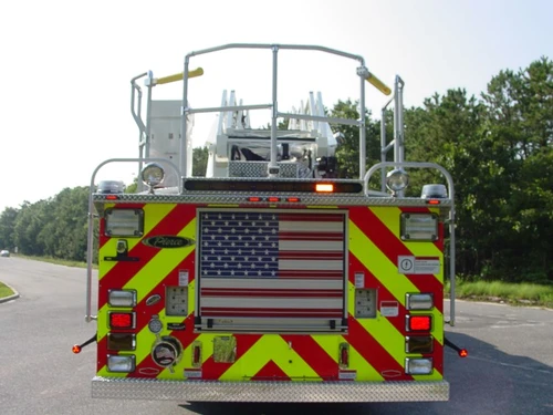 Straight rear view with red-yellow chevrons, rear intake and discharge fittings, and platform railings above.