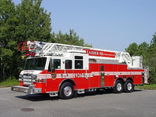 Front-right wide exterior view showing the cab, side compartments, front outrigger, and ladder bed.
