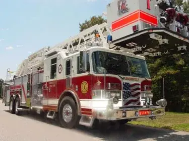 Aerial ladder truck front-left exterior view showing enclosed cab and ladder sections