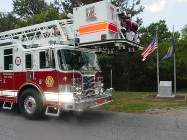 Front-left exterior view showing bumper, cab, and ladder tip above cab