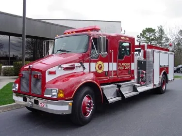 Front-left exterior view of pumper showing long hood cab and side pump panel area