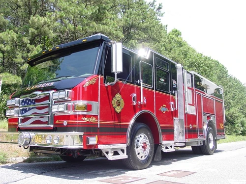 Front left exterior view showing the chrome bumper, flag-style grille, and side compartment body.