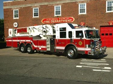 Aerial ladder truck front-left exterior view showing ladder sections and tandem rear axles