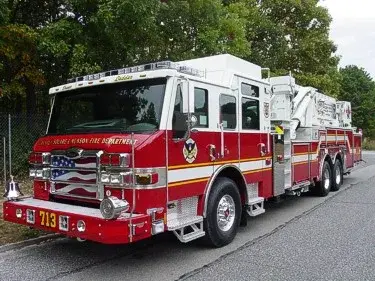 Aerial ladder truck front-left exterior view showing enclosed cab and ladder bed