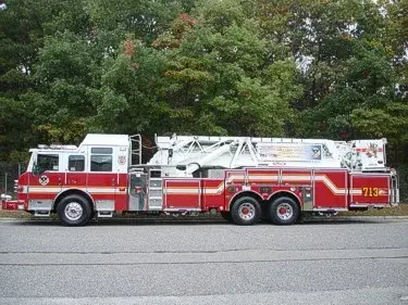 Driver-side full profile showing long ladder bed and tandem rear axles