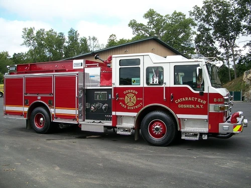 Driver-side profile of a pumper showing the enclosed cab, pump panel section, and rear body compartments.