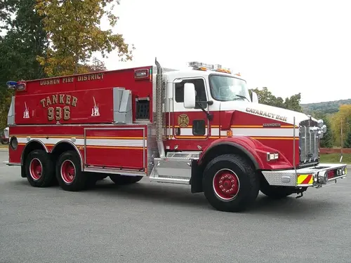 Driver-side profile view of a tanker with commercial cab, side compartment doors, and tandem rear axles.