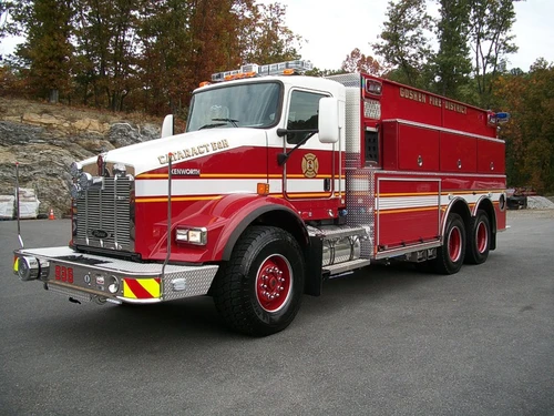 Front-left exterior view showing the grille, bumper, cab, and side tank body compartments.