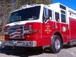Wide front-left view of the pumper parked roadside with full side body visible.