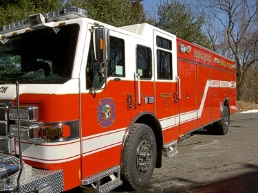 Front-left exterior view of heavy rescue truck showing cab and long side body