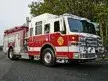 Wide front-right view of the pumper parked roadside with full side body visible.