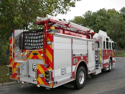 Rear-right exterior view with red-yellow chevrons, rear hosebed netting, and rear body fittings.