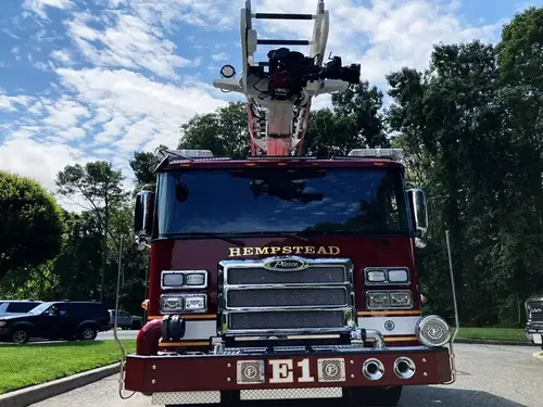 Aerial ladder truck front-right exterior view showing cab, grille, and front wheel area