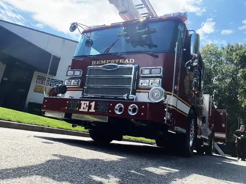 Aerial ladder truck driver-side profile view showing ladder bed and side compartments
