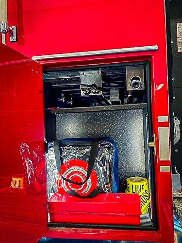 Open side compartment showing hose reels and equipment stored in lower bay