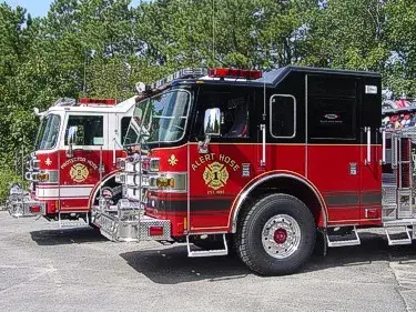 Two-apparatus lineup front-quarter view showing white and black cabs