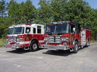 Two-apparatus front-quarter view showing bumpers, cabs, and wheel areas
