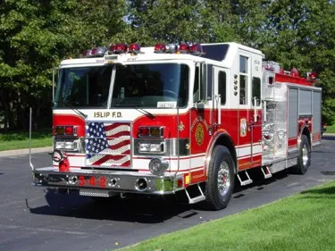 Front-left exterior view of pumper showing chrome bumper and American-flag grille insert