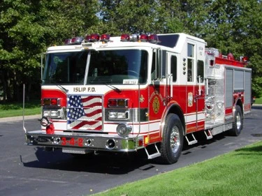 Front-left exterior view of pumper showing chrome bumper and American-flag grille insert