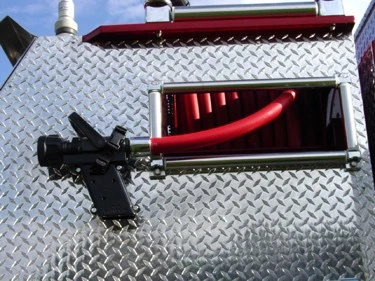 Rear hosebed side opening close-up showing red hose and mounted nozzle