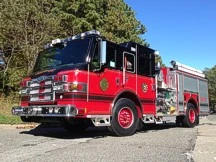 Wide front-left view of the pumper parked roadside with full side body visible.