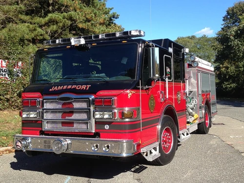 Front-left close view showing grille, bumper, warning lights, and exposed pump panel fittings.