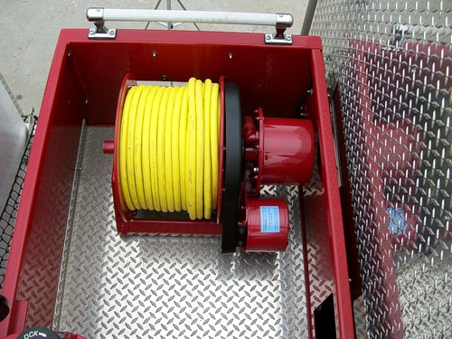 Open hose reel compartment showing yellow hose roll on a reel