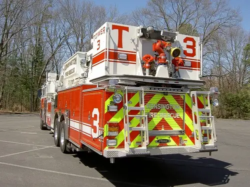Rear right angle showing chevron-striped rear, bucket-mounted master stream plumbing, and rear access ladders.