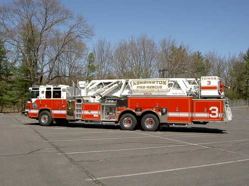Wide left-side profile showing full ladder length, turntable controls, and tandem axle wheel area.