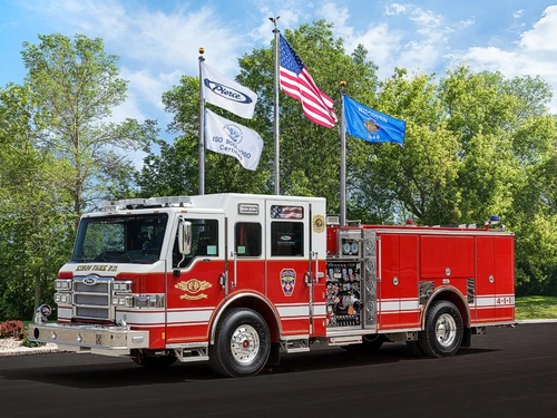 Front-left exterior view of a pumper showing the cab, pump panel controls, and rear body compartments.