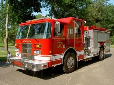 Front left exterior view of the pumper showing chrome bumper, cab profile, and side pump panel section.