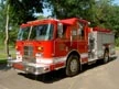 Wide front right view of the parked pumper showing cab, bumper, and side compartments.