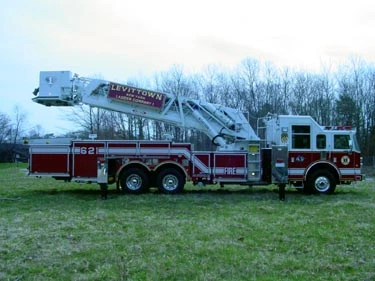 Passenger-side full profile showing tower ladder body, bucket, and tandem rear axles