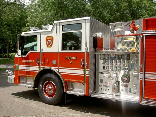Left-side cab and pump area close-up showing gauges, valves, discharges, and front wheel section.
