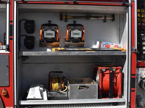 Open side compartment showing chargers, lights, and equipment shelf