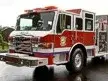 Pumper front-left exterior view on wet pavement showing cab and side compartments