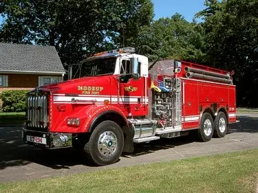 Front-left exterior view of tanker truck showing long hood, tandem rear axles, and side pump area