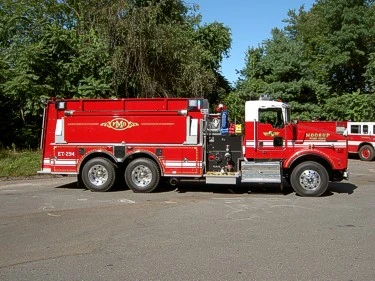 Passenger-side full profile showing long body, rear wheel group, and top hose rail