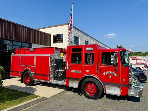 Full right-side profile of the pumper showing roll-up compartments, pump panel section, and wheel/tire area.