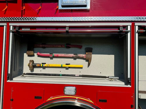 Close-up of a side tool compartment above the rear wheel with mounted striking and prying tools.