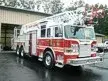 Wide front-right view of a pumper parked in front of the station with full side profile visible.