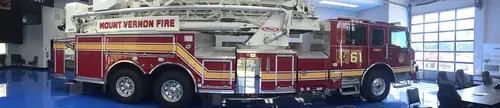 Wide side profile view of the tiller aerial parked indoors with full ladder and body length visible.