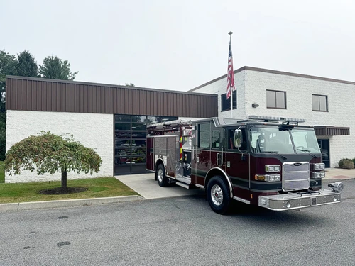Wide front-right exterior view of the pumper parked outside the station with cab and side body visible.