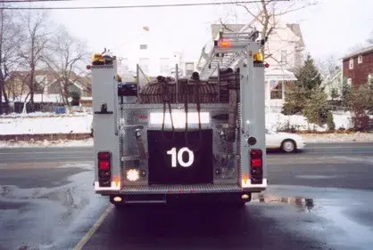 Straight rear view showing loaded hosebed, rear step platform, and tail lights.