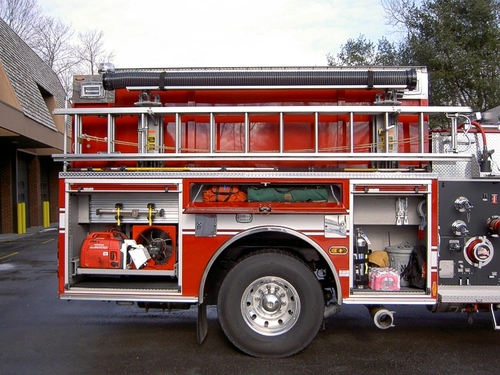 Passenger-side mid-body view showing side hosebed rails and rear wheel area