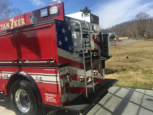 Rear right corner view showing rear ladder, tailboard step, warning lights, and rear connection panel.