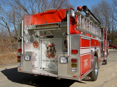 Rear-right exterior view showing rear body panel, hosebed cover, and ladders